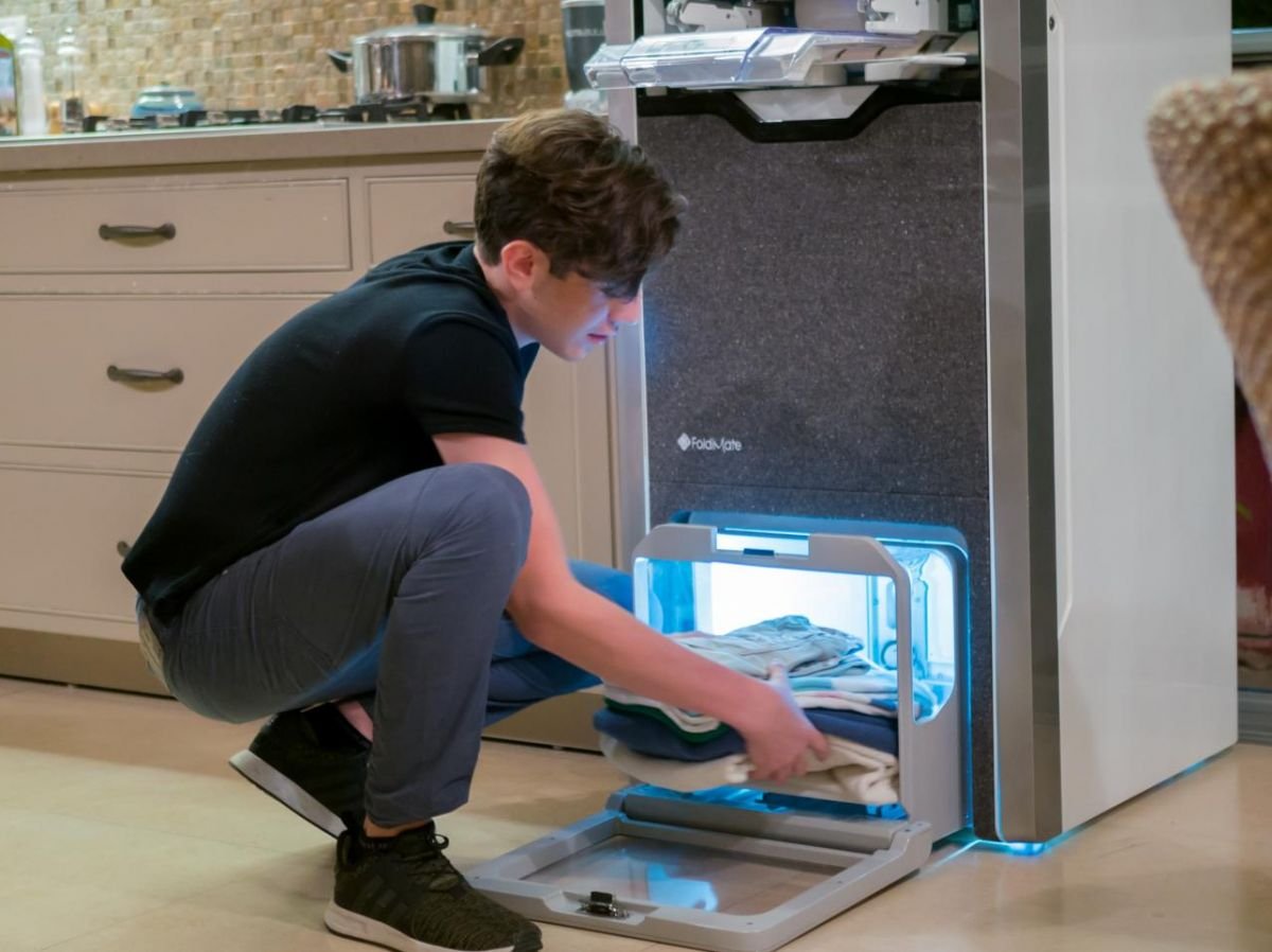 A young boy removes his impeccably folded and ironed clothes from the FoldiMate machine, offering fast, quality results. Find out how this innovative solution simplifies folding and ironing on de.foldimateofficial.com.